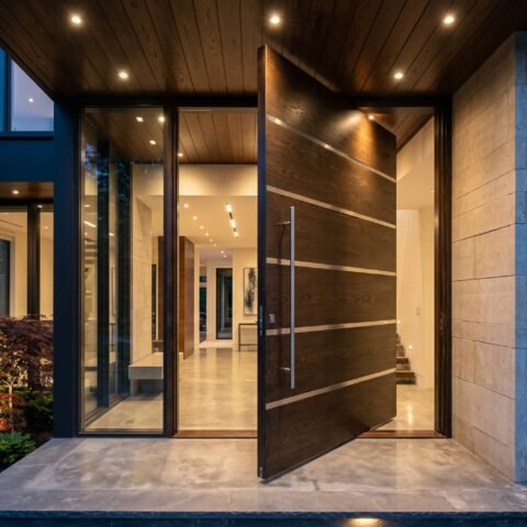 Shop a modern double heighted wood pivot door with rich dark wood finish, horizontal metal inlays, oversized proportions, and a premium architectural design for luxury entrances.