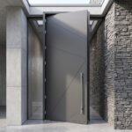 Double heighted modern gray architectural entry door with geometric diagonal detailing and long vertical handle