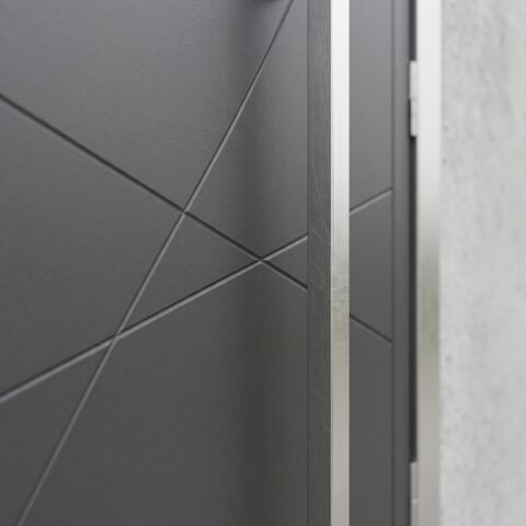 Double heighted modern gray architectural entry door with geometric diagonal detailing and long vertical handle