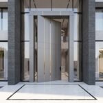Tarkhan Door double heighted white pivot door with vertical gold accents and minimalist handle in a modern luxury interior